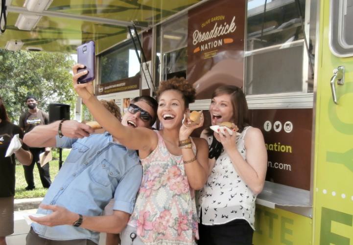 Three guests taking a group selfie with breadstick sandwiches in front of the Breadstick Nation food truck